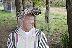A senior Hispanic man in his seventies wears a traditional Colombian poncho called \