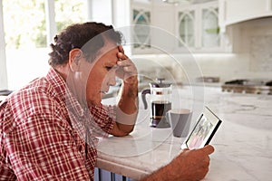 Senior Hispanic Man At Home Looking At Old Photograph