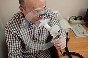 Senior hispanic man man testing breathing function by spirometry