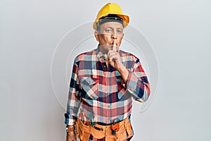 Senior hispanic man wearing handyman uniform asking to be quiet with finger on lips