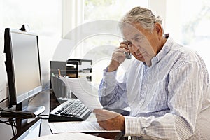 Senior Hispanic man working on computer at home