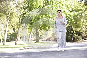 Senior Hispanic Woman Jogging In Park