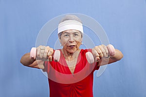 Senior hispanic woman in a sweatband lifting weights photo