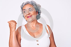 Senior hispanic woman wearing casual clothes smiling with happy face looking and pointing to the side with thumb up