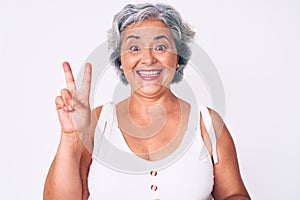 Senior hispanic woman wearing casual clothes smiling with happy face winking at the camera doing victory sign