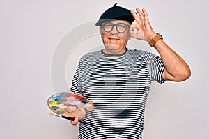 Senior hoary artist man wearing french beret drawing using paintbrush and palette with colors doing ok sign with fingers,