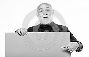 Senior holding blank sign board and looking at camera. Man bold head and gray beard hold poster for advertisement copy