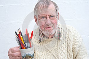 Senior holding a mug of pens and pencils. photo