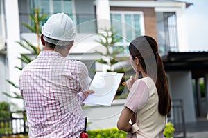 Senior home inspector explains Inspection results with homeowner, handyman holding clipboard and after checking details before