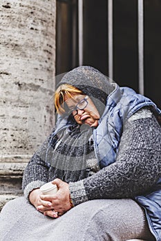 Senior homeless lady sleeping on the sidewalk in Rome, Italy
