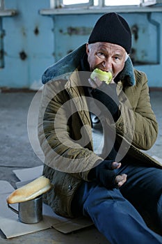 Senior homeless man eating an apple