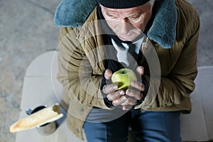 Senior homeless man holding an apple photo