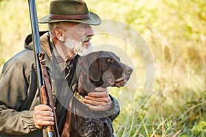 Senior hunter with dog in forest