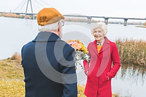 senior husband gifting bouquet of flowers to his