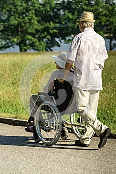 Senior husband pushing wife in wheelchair