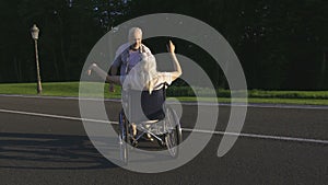 Senior husband spinning wife on wheelchair in park