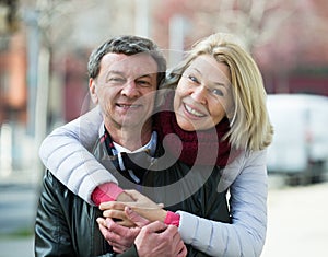 Senior husband and wife cuddling outdoors