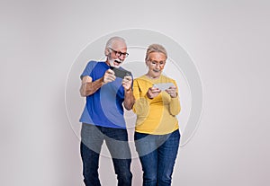 Senior husband and wife playing video games over mobile phone and screaming on white background