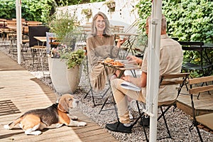 Senior husband and wife and their beagle dog relaxing at the summer cafe