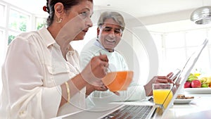 Senior Indian Couple Using Laptop And Digital Tablet At Home