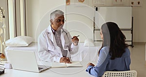 Senior Indian practitioner man consulting young female patient