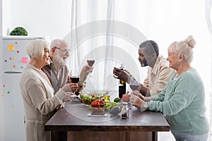senior interracial friends holding glasses with