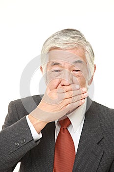 Senior Japanese businessman making the speak no evil gesture