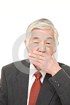 Senior Japanese businessman making the speak no evil gesture