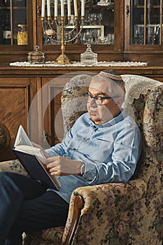Senior Jew reading book in traditional home