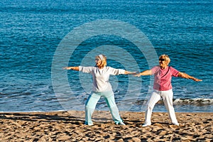 Senior ladies doing yoga on beach.