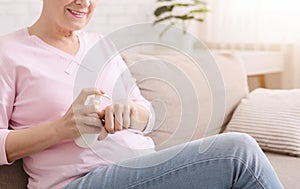 Senior lady applying moisturizing cream on hands