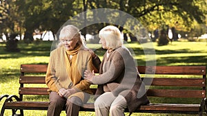 Senior lady comforting old friend about her loss, sitting on bench in park