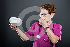 Senior lady doctor covering bad noise from lunch box