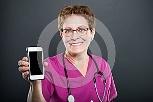 Senior lady doctor showing blank screen smartphone