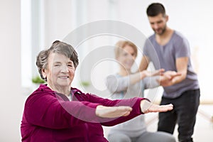 Senior lady exercising during group physiotherapy at rehabilitation center