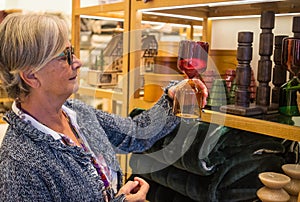 The senior lady in the home improvement store looks with interest at the two-tone hourglass. Many curious objects displayed around