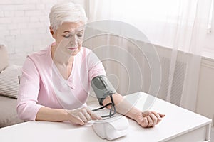 Senior lady with hypertension measuring blood pressure herself