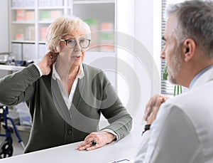 Senior lady with neck pain in the doctor`s office