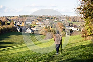 Senior lady nordic walking in the countryside landscape