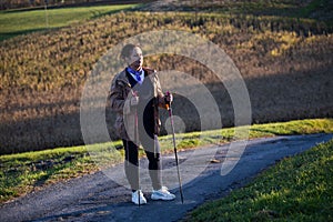 Senior lady nordic walking on the countryside road