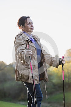 Senior lady nordic walking portrait in the countryside landscape