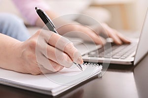 Senior lady noting information from internet using laptop