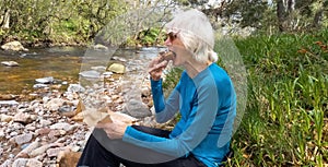 Senior lady resting and eating chocolate brownie following a long walk