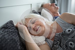 Senior lady sleeping in comfortable bed with husband