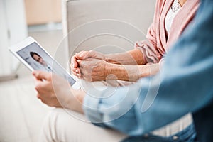 Senior lady and young woman having video call with doctor