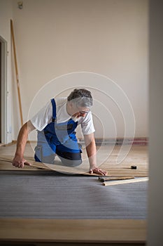 Senior landlord lying parquet floor board/laminate flooring in a rental appartement