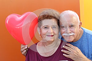 Senior Latino Couple holding a heart balloon