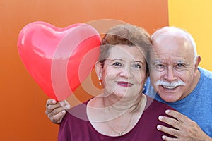 Senior Latino Couple holding a heart balloon