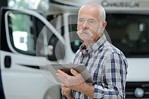 Senior logistics man next to container truck with tablet