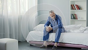 Senior lonely person sitting on couch and thinking about his health, morning